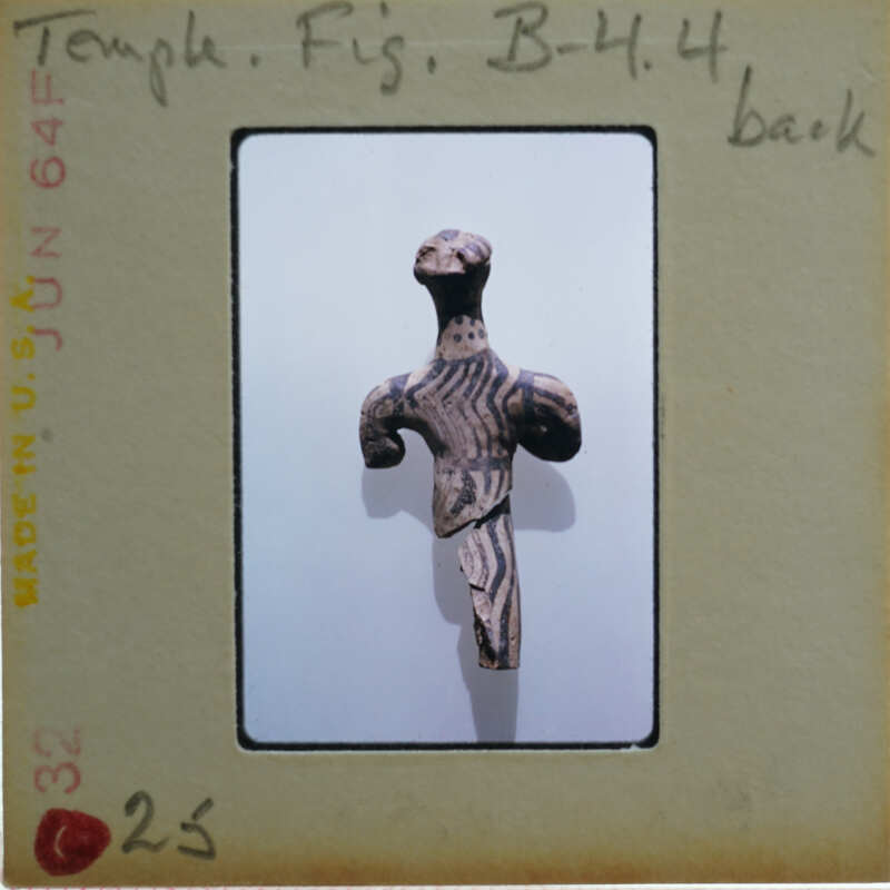 An old, possibly African, carved wooden sculpture of a humanoid figure with intricate designs on display.