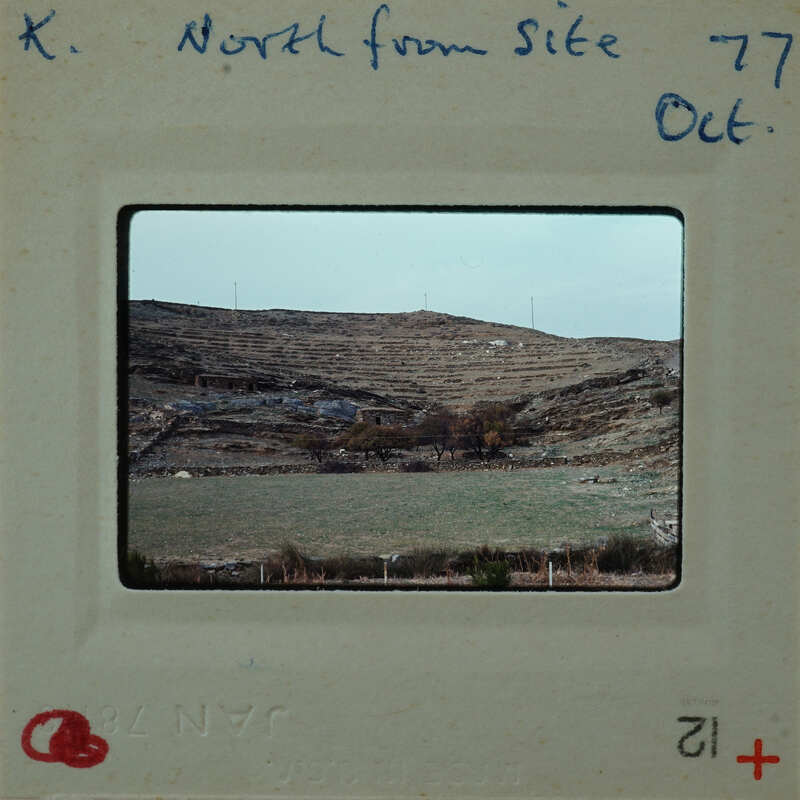 The image is a photograph of a landscape with hills, greenery, and buildings, presented on a film strip with handwritten notes.