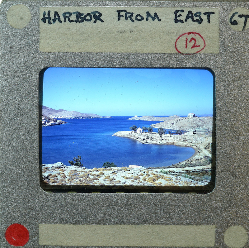 A vintage film strip with a scenic harbor image and handwritten notes on the border.