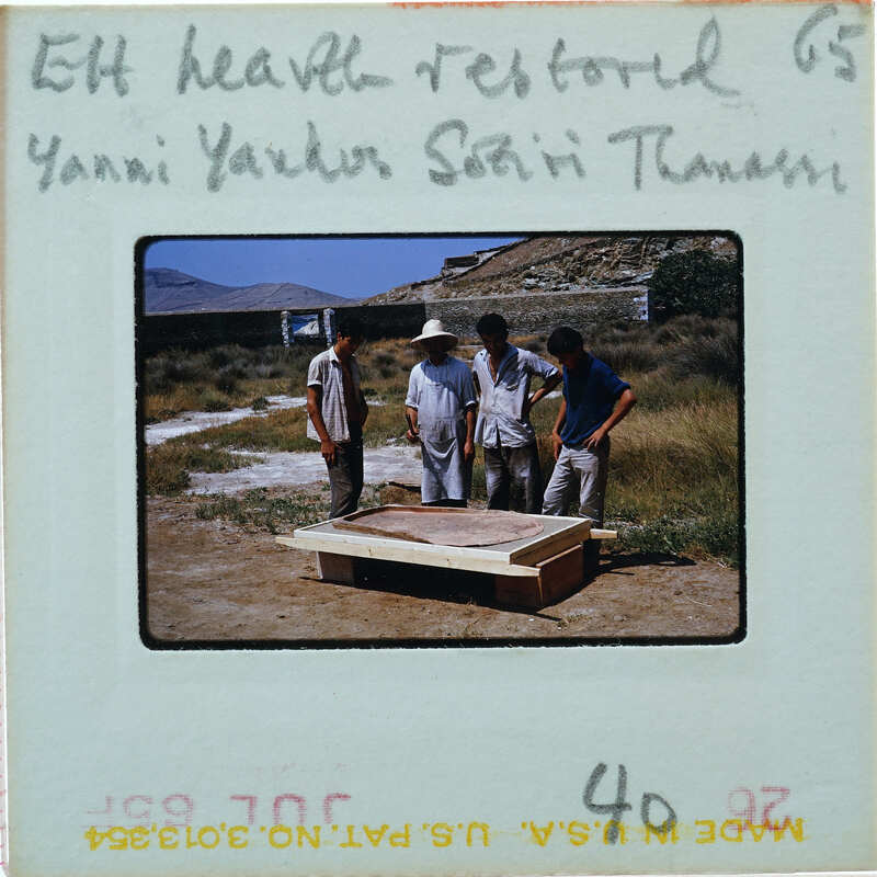 Four men standing around a large wooden structure with mountains in the background.