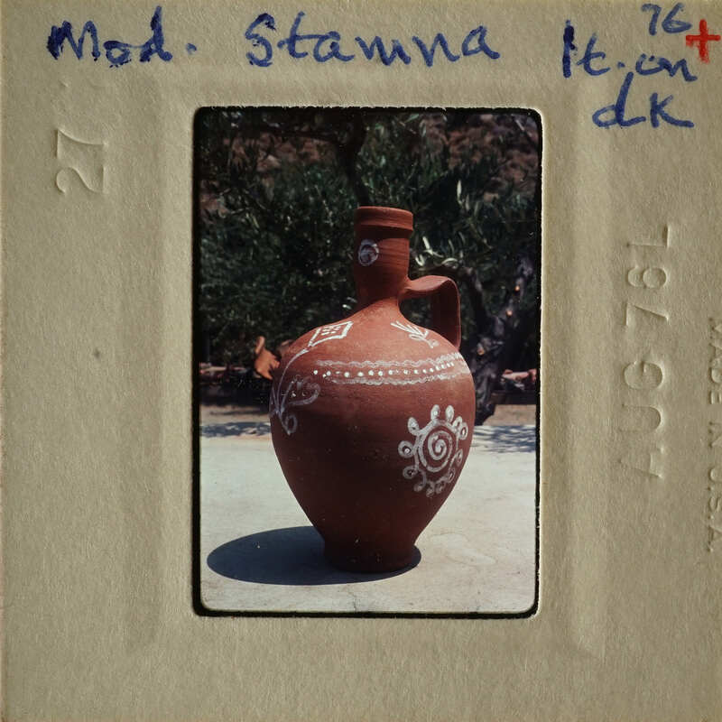 A large, intricately decorated terracotta vase with blue patterns on a stone surface.