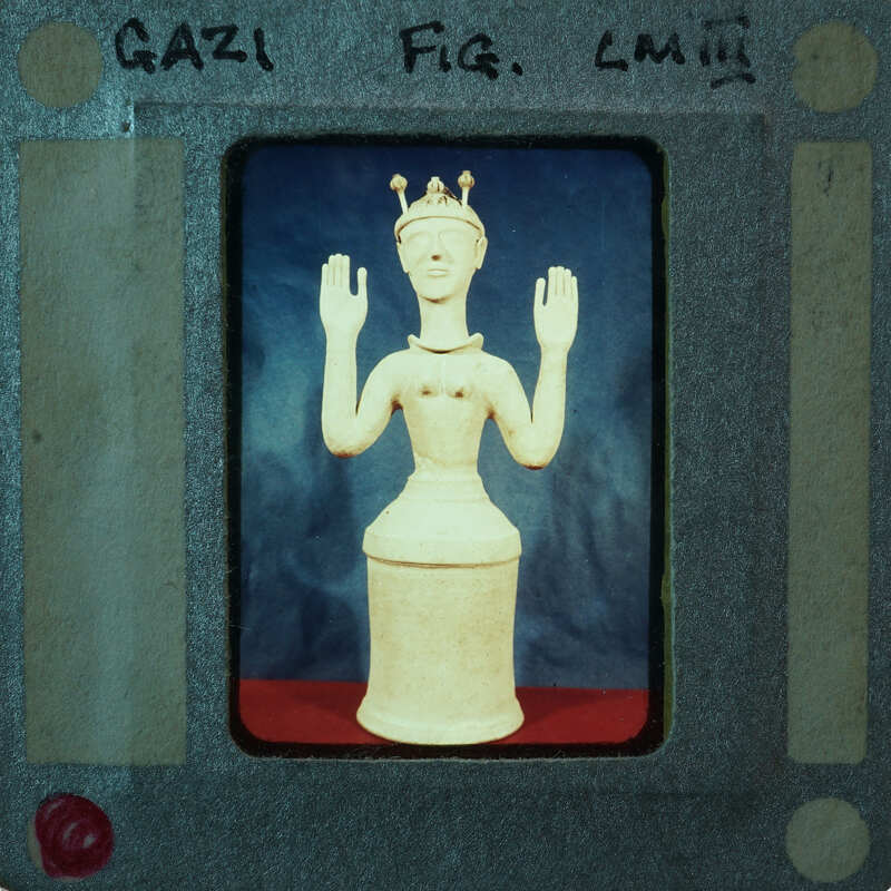 A small figurine of a person with a crown, placed on top of a cylindrical base.