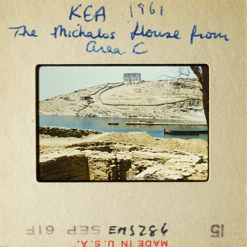 A photograph showing an ancient cityscape with stone ruins and water, possibly from a historical site like The Michalos House Area C.