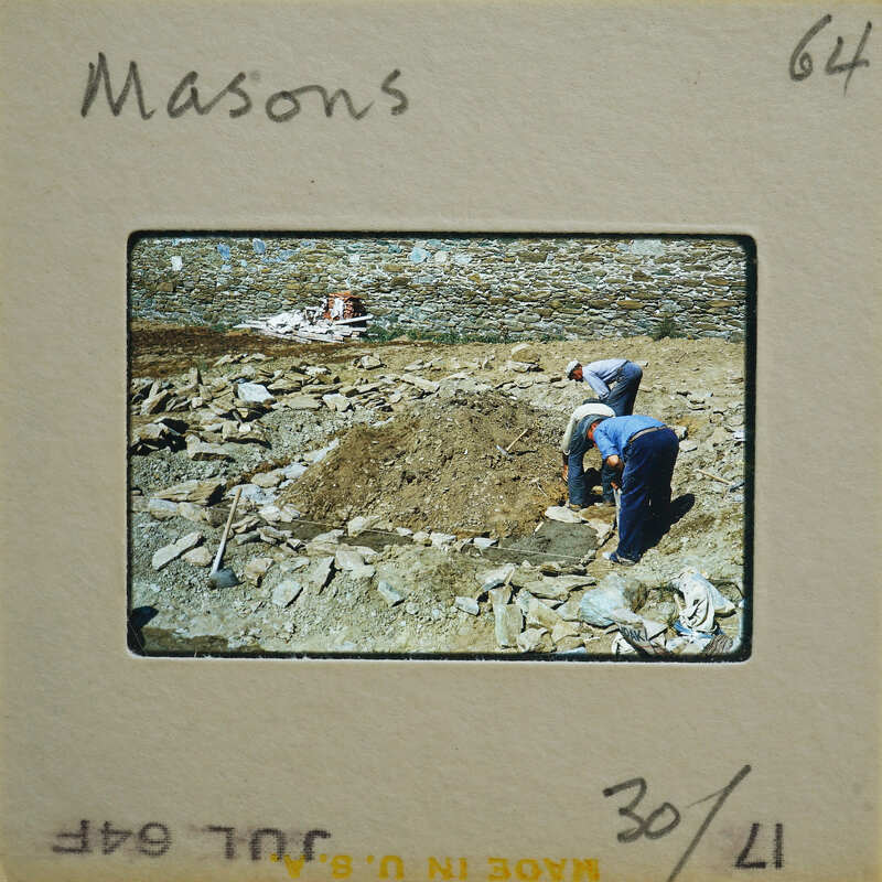 Two people working on a construction site with dirt and rocks.