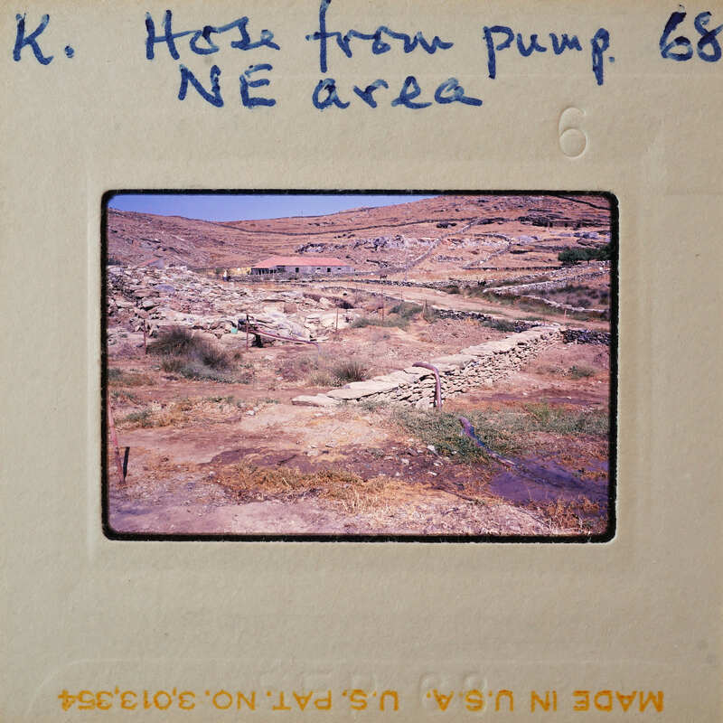 A vintage photo of a dry, rocky landscape with sparse vegetation and stone structures.