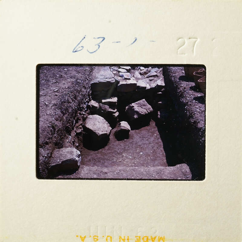 Old photograph of a stone-lined pit with dirt and debris around it.