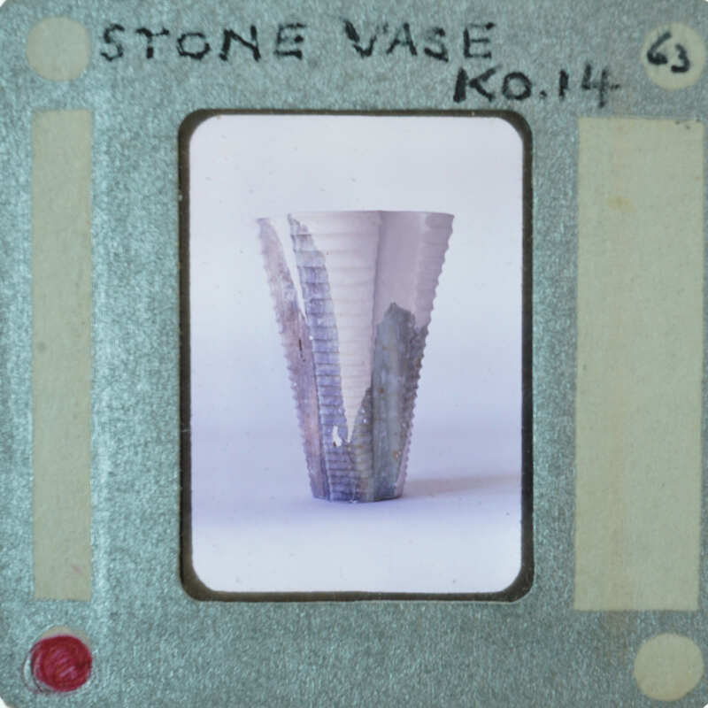 A photograph of a stone vase with a label on it.