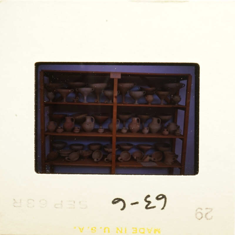 Photograph of an organized display case filled with various pottery items.