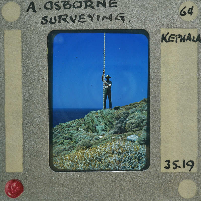 Man standing on rocky cliff with ocean below, captured in vintage Polaroid photo format.