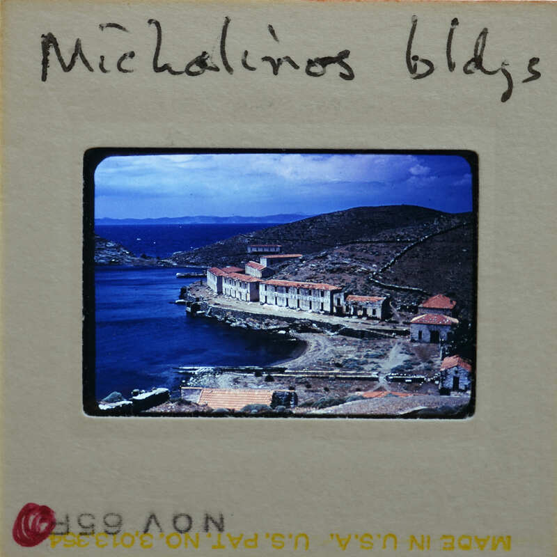 A vintage postcard featuring a scenic coastal village with houses and boats on the water.