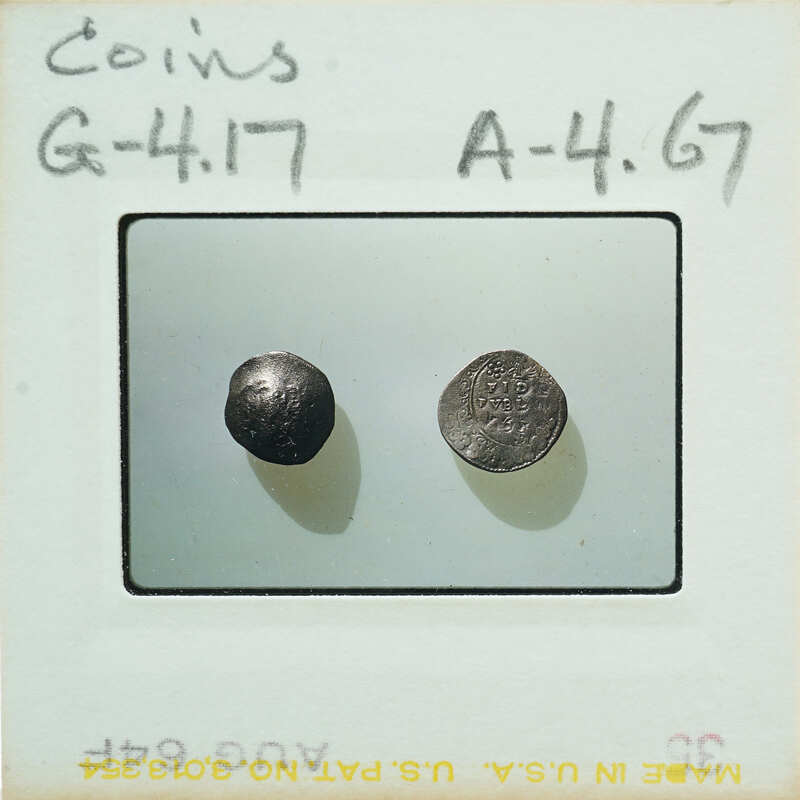 Two old coins displayed on a white surface with labels and numbers written on them.