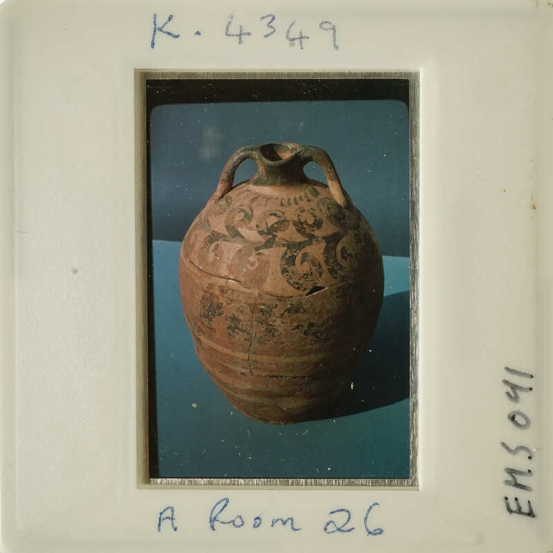 Ancient vase with intricate designs, photographed on a blue surface.