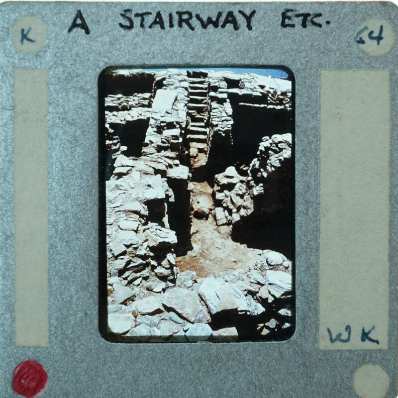 A photograph of a stone staircase within an old structure, presented on a film strip with writing and numbers indicating its position.