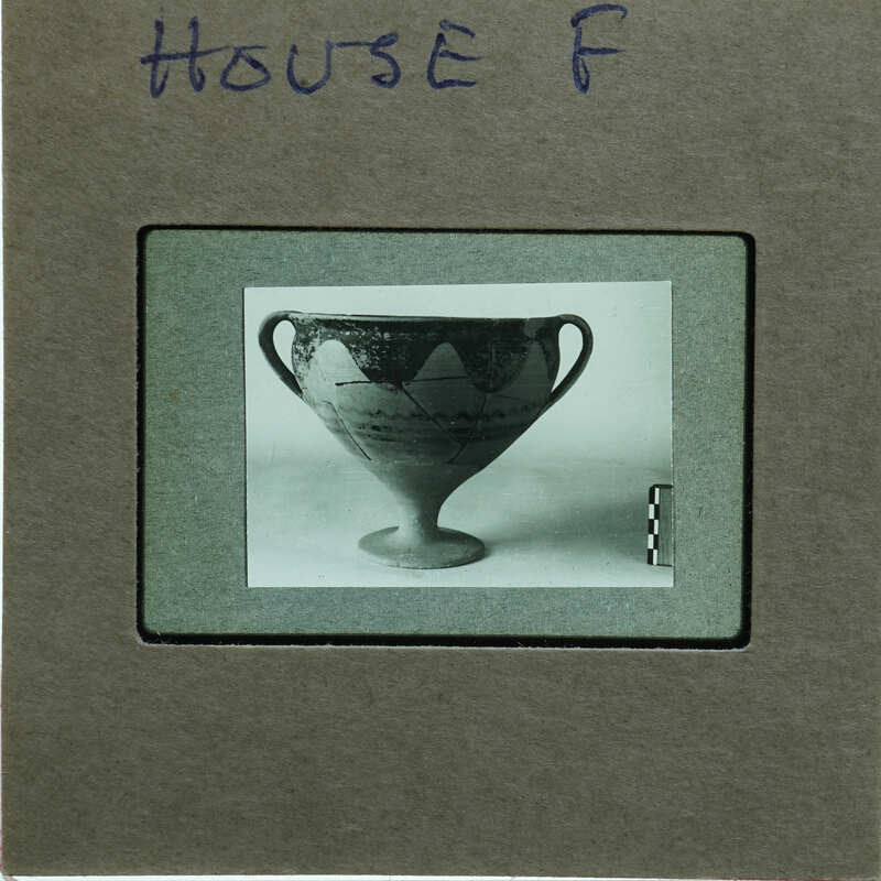 Reassembled two handled cup in profile on table.