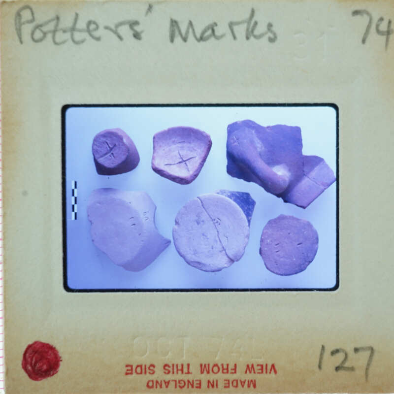 A collection of clay pottery shards with a label indicating they are "Potter's Marks" from an archaeological site.