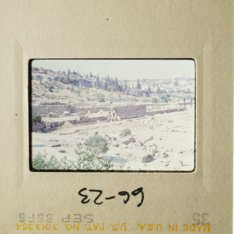 This is an image of an old photograph with a handwritten note on it, depicting an ancient cityscape with ruins and modern buildings in the background.