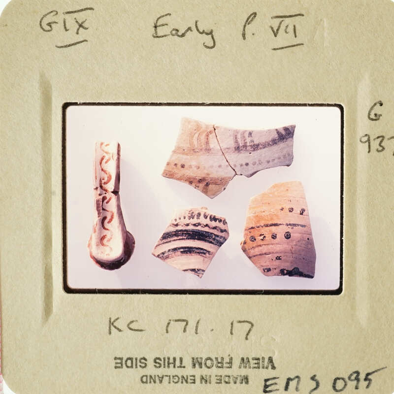 Pile of ancient pottery shards with intricate designs on white surface.