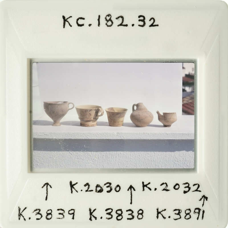 Old vases on display with labels and measurements written on them.