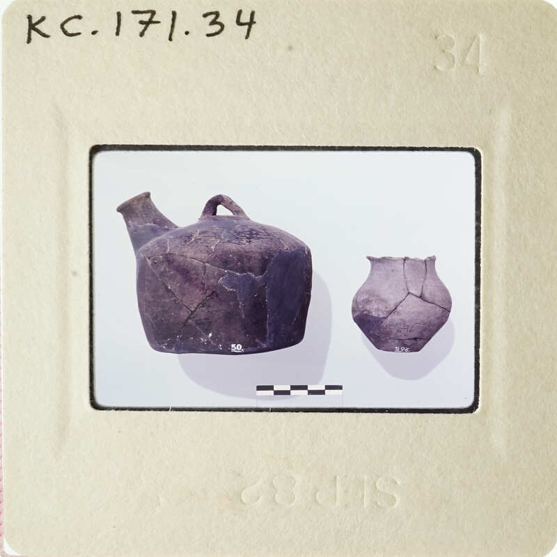Photograph of ancient pottery on display, including a large jug and two smaller vases.