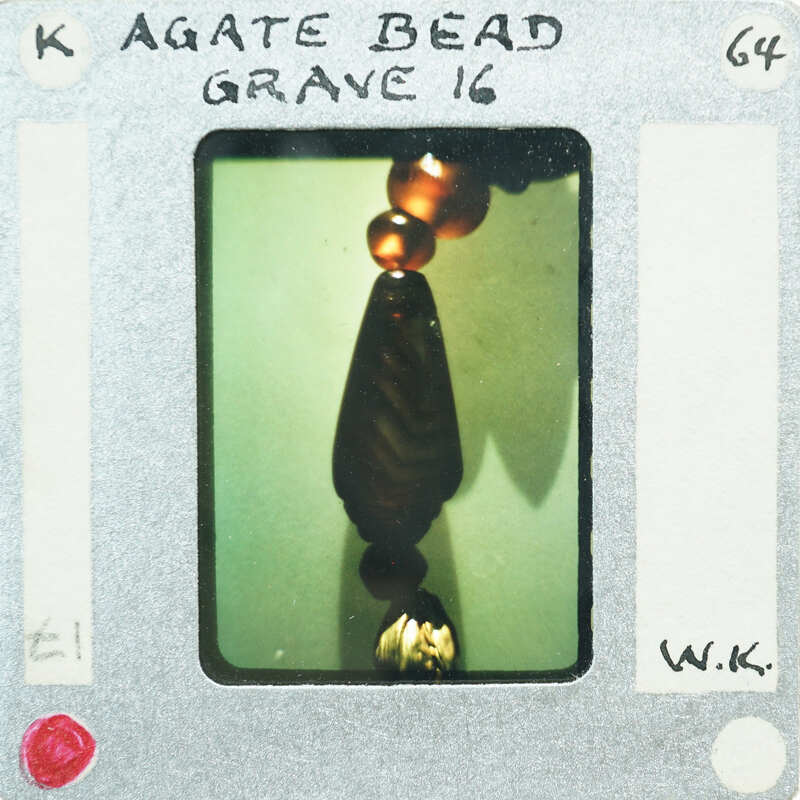 A photograph of a necklace detail with beads on a film strip.