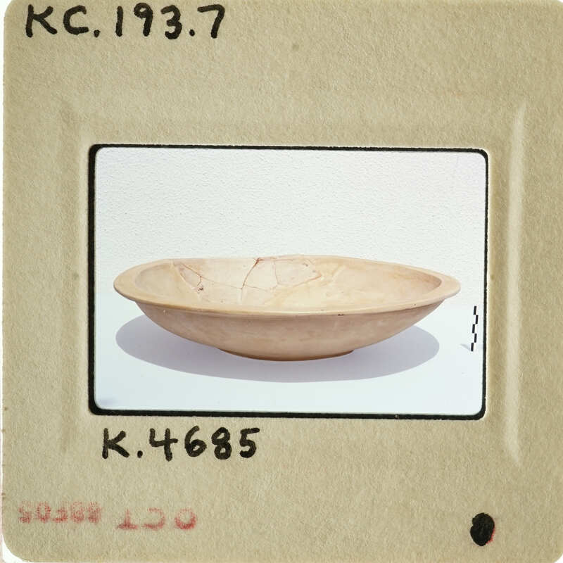 A photograph of an antique bowl with visible cracks and imperfections.
