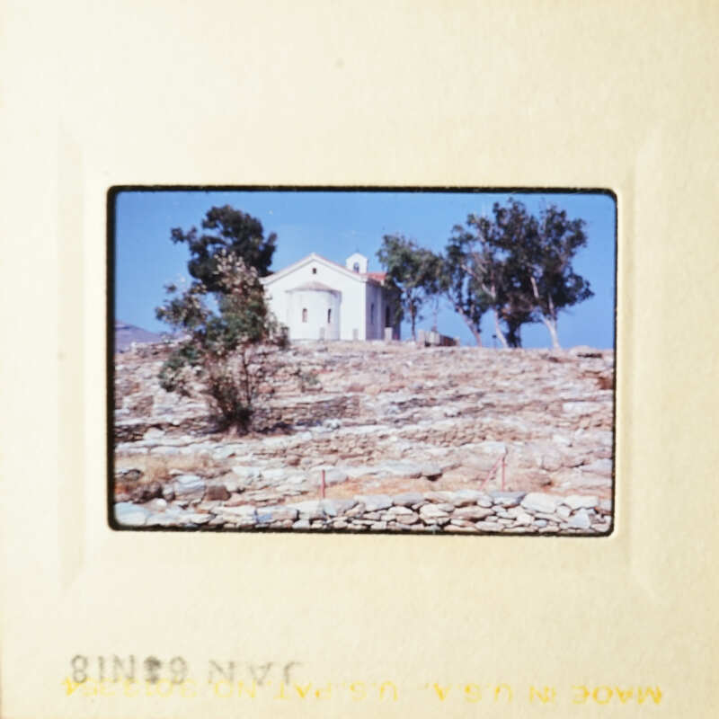 A church on top of a hill with trees and blue sky.