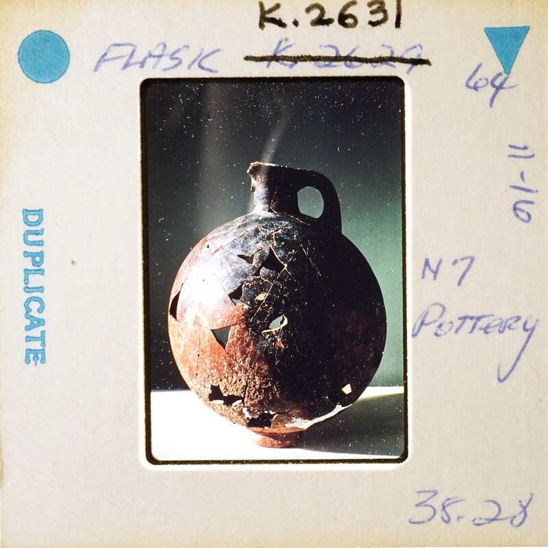 An old clay pot with a unique design, photographed on film and marked as "Pottery".