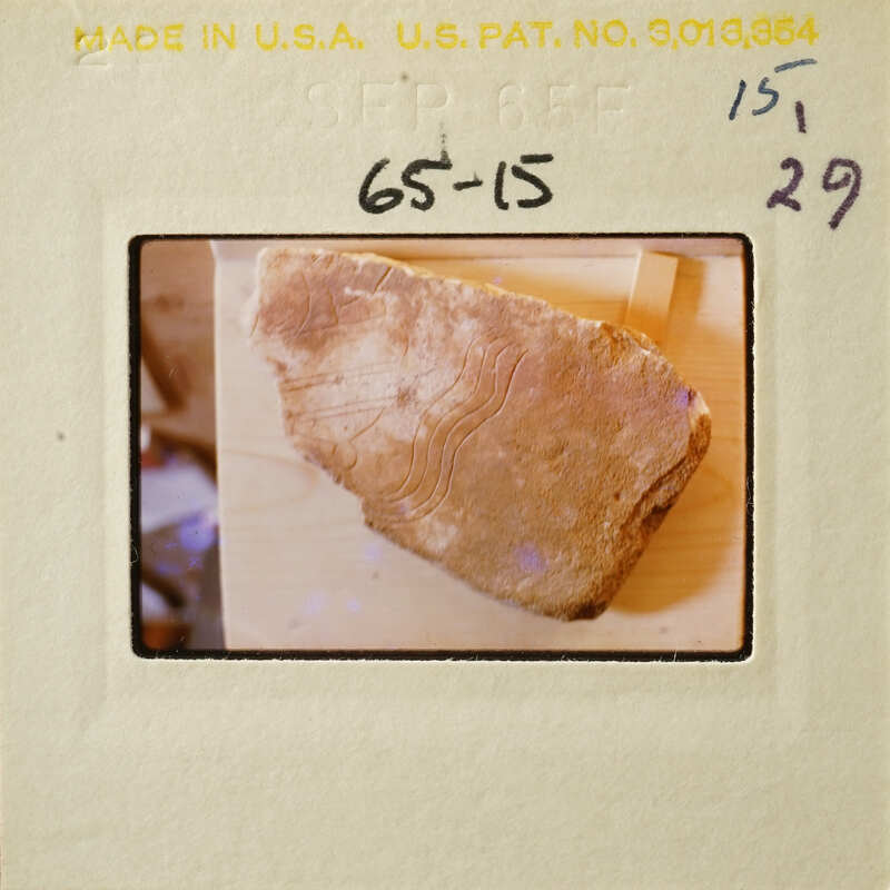 Old photograph of a rock with markings on a wooden surface.