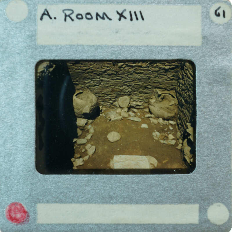 A small room with stone walls and a few pots on the floor, captured through a peephole viewer.