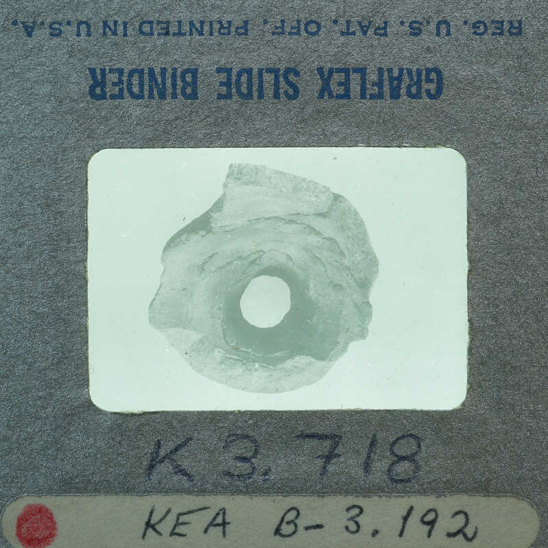 A small, circular object with a hole in the center, placed on a label with handwritten numbers and letters.
