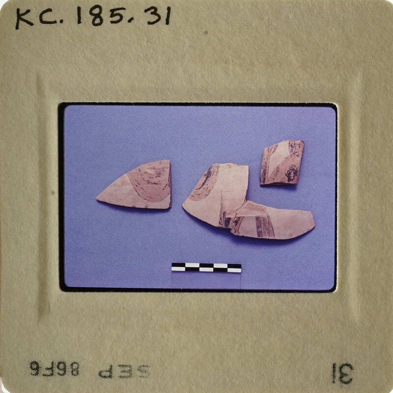 Photograph of ancient pottery shards with markings on them, displayed on a blue background.