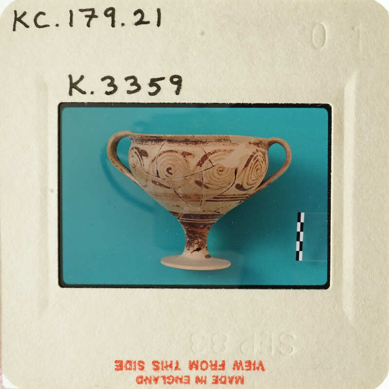 Ancient Greek vase with intricate designs, photographed on a blue background and marked with "K.3765".