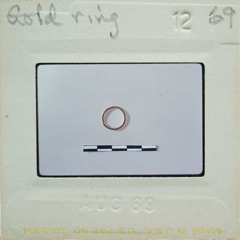 Gold ring on a piece of paper with handwritten notes and labels.