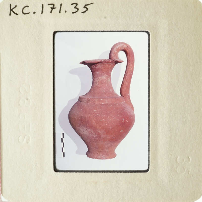 Ancient clay pottery artifact with handle and spout.