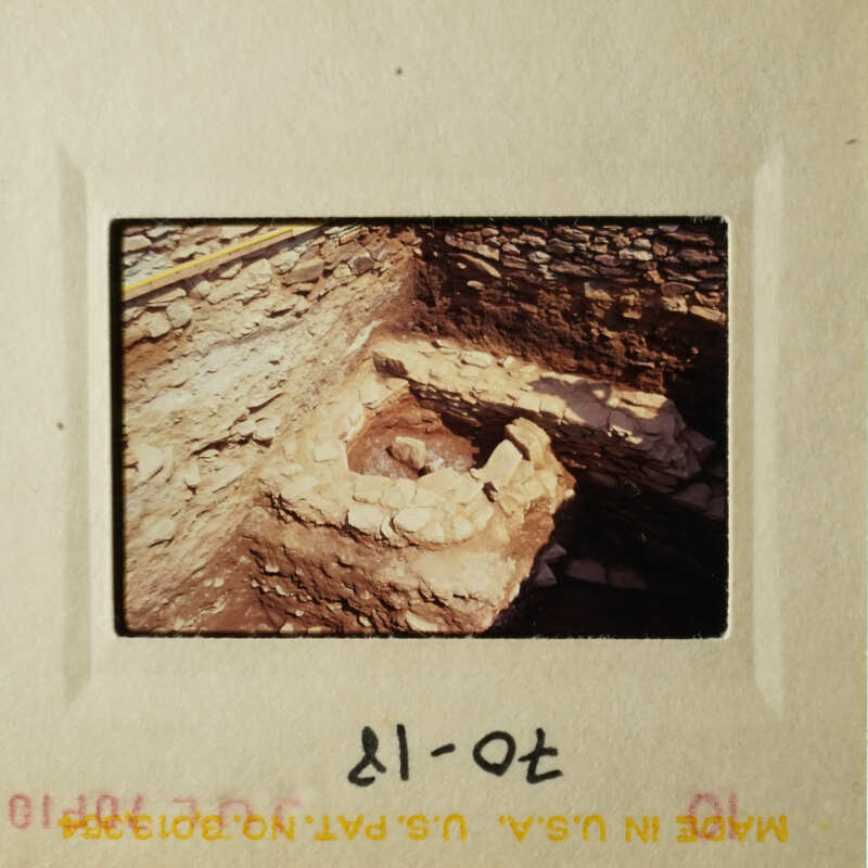 Old photo of an ancient stone structure, possibly ruins, with a small opening at the bottom.