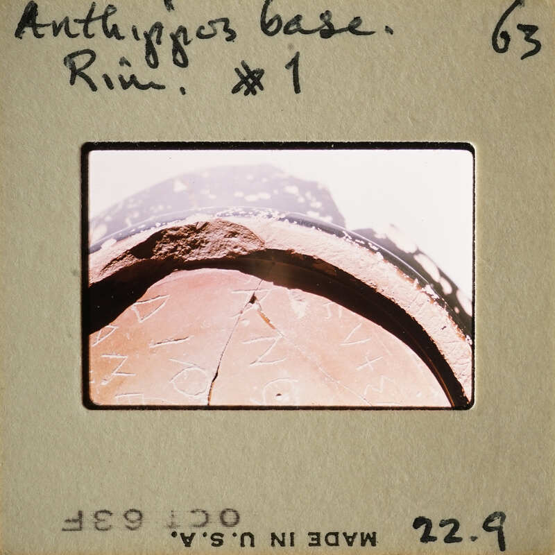 Ancient artifact with writing, possibly Greek, on a clay tablet.