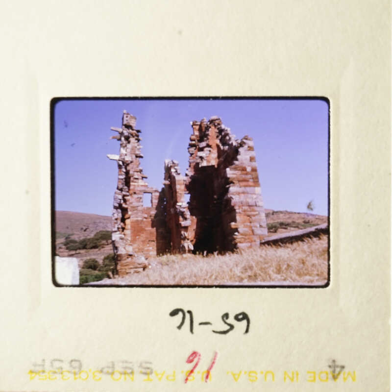 The image shows an old, abandoned building with crumbling walls and a clear blue sky in the background.