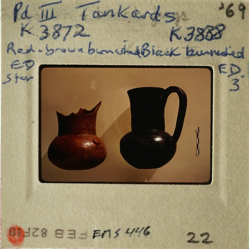 Two vases displayed on a white surface, with one being brown and the other black.