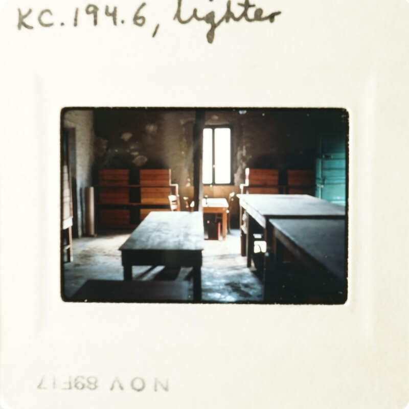 The photo shows an empty room with wooden tables and benches, captured on a film strip.