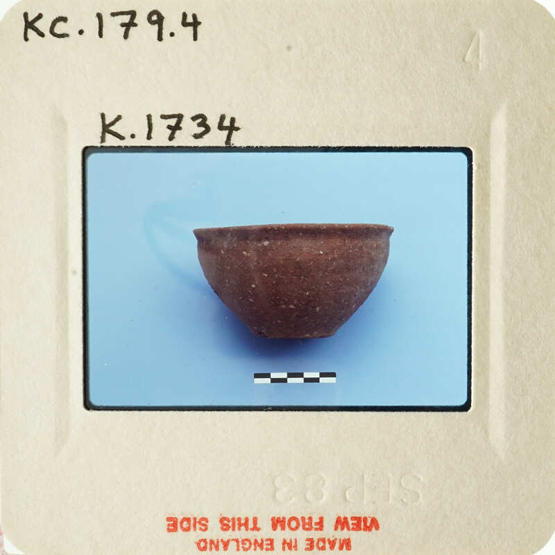 Small brown clay bowl on blue surface with white markings.