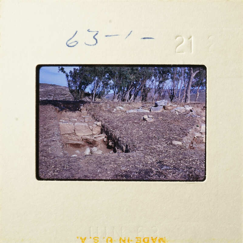 "Old ruins with rocks and vegetation, captured on an aged photographic film strip."