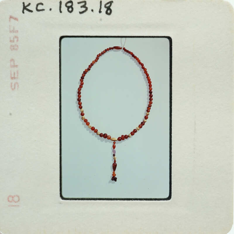 A photo of a red rosary bead necklace with a cross pendant.