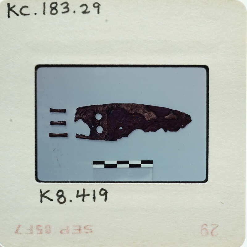 Fragment of metal blade from side with rivets on left.