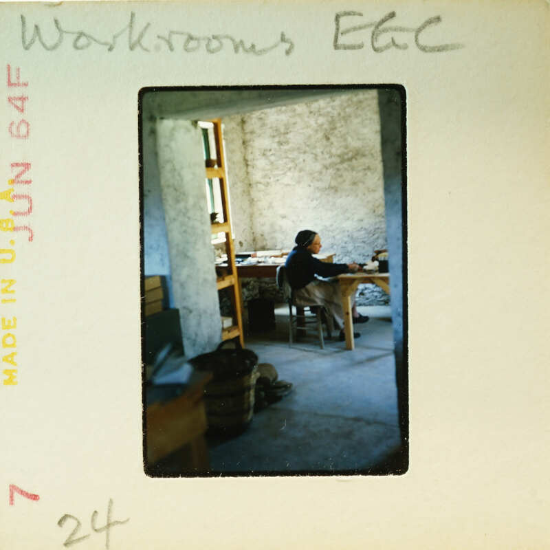 Man sitting at a desk in an old building with stone walls and wooden furniture.