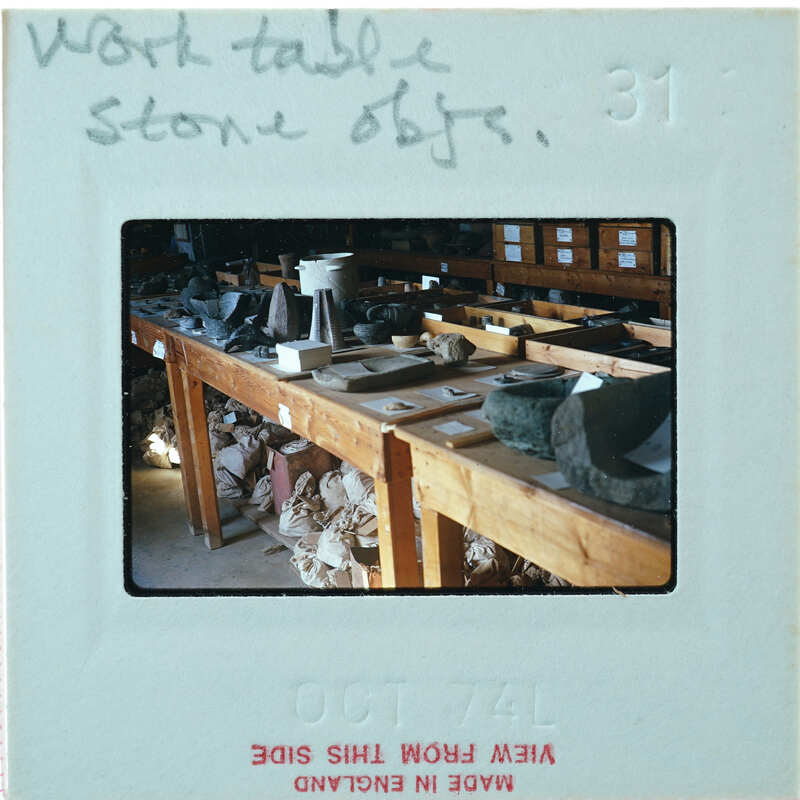 A photo of a cluttered work table with various objects and materials, including rocks, on it.