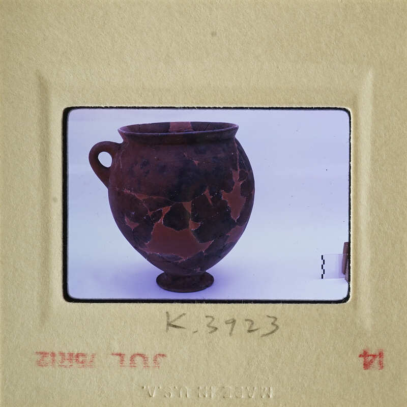 Ancient ceramic vase with dark brown and lighter tan glaze, photographed on a white background.