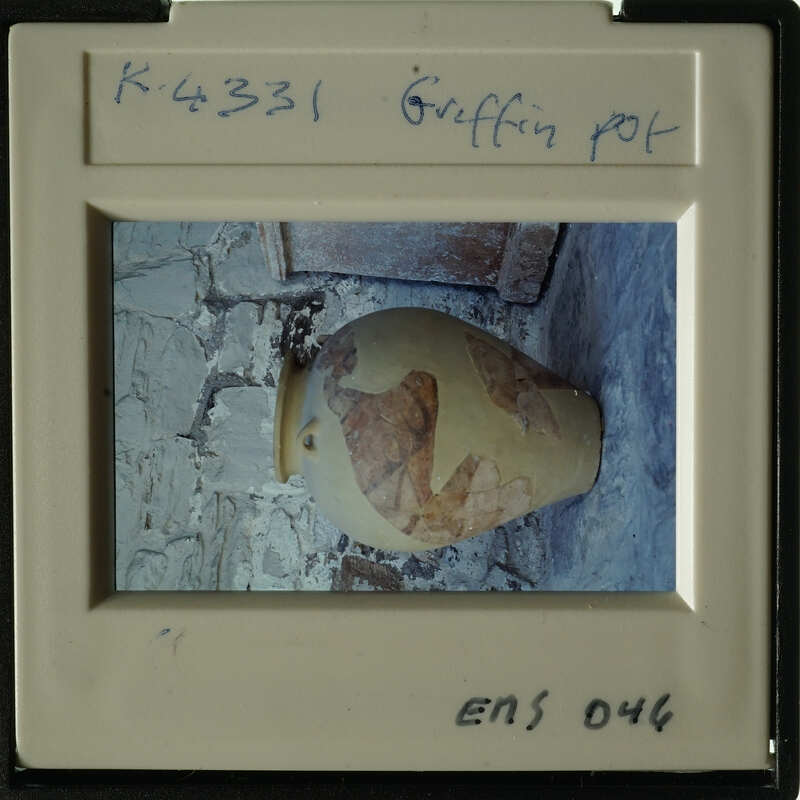 Ancient vase with visible cracks and peeling paint, sitting on stone floor.