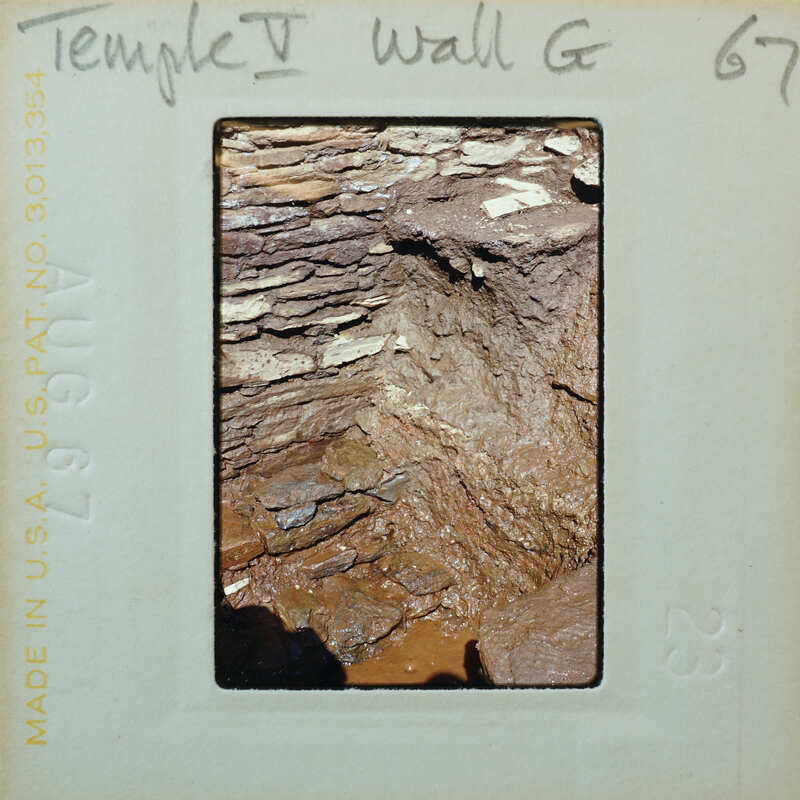 Interior corner of stone wall with muddy floor.