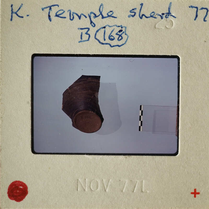 Ancient coin on display with a label and date stamp.