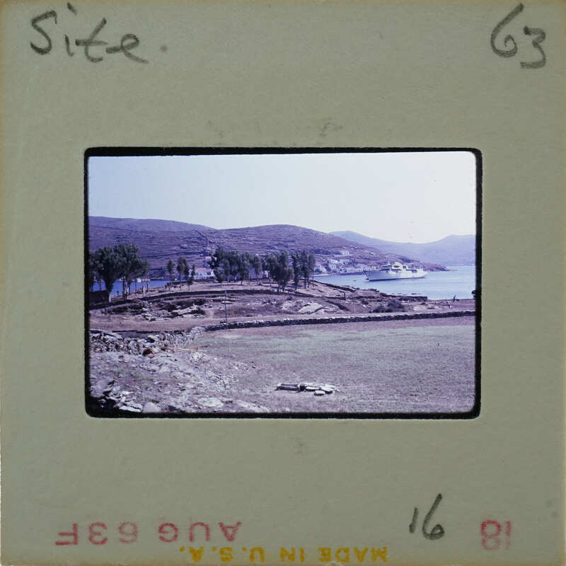 A vintage photograph of a coastal landscape with mountains, water, and vegetation.